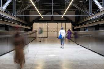 gallery visitors walk through a set of doors and a corridor with markings on the floor