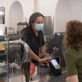 a person stands at a till desk and orders something from a member of cafe staff