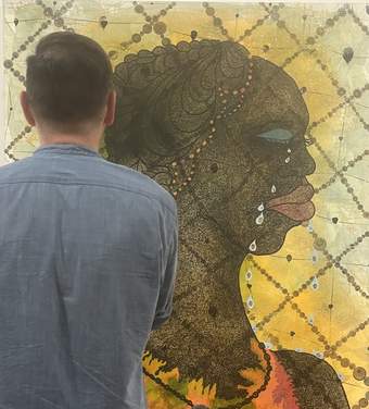 A person looking at No Woman, No Cry by Chris Ofili