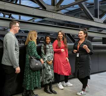 A group of five people talking at Tate Modern