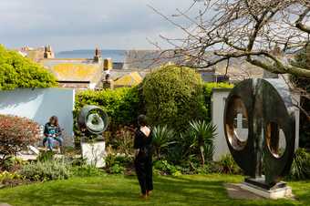 a woman stands in the Barbara Hepworth garden looking out to the view